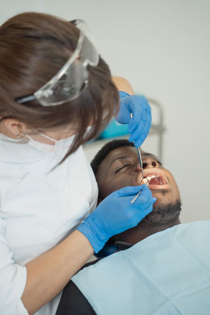 Dentist examining patient's teeth using dental tools in a clinic setting.